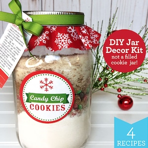 May include: A clear glass jar filled with cookie ingredients, topped with a red and white snowflake fabric and a green ribbon. A red and white label reads "Candy Chip COOKIES". A red circle with white text reads "DIY Jar Decor Kit not a filled cookie jar!" and a blue rectangle with white text reads "4 RECIPES".