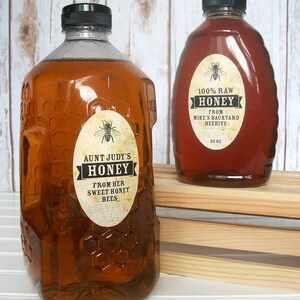 Vintage looking oval honey labels on the front of honey bottles filled with honey. Label art has a realistic honey bee up top with printed text for 100% Raw honey.