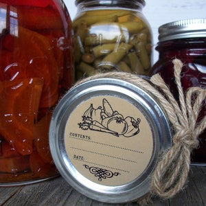 May include: Three glass jars with lids, two with brown twine tied around the lids. The jar in the center has a brown paper label with a black illustration of vegetables and the text "CONTENTS: DATE:".