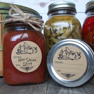 May include: Three glass jars with brown paper labels. The jar on the left contains red salsa with a label that reads "Hot Salsa 2019". The jar in the middle contains green beans and the jar on the right contains red peppers.