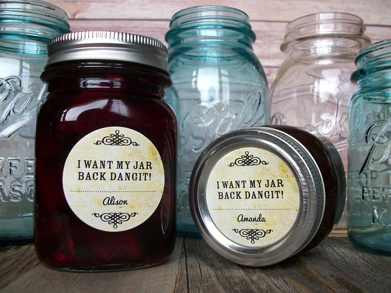 May include: Two glass jars with silver lids and labels that say "I want my jar back dangit!" One label has the name Alison and the other has the name Amanda. The jars are sitting on a wooden surface.