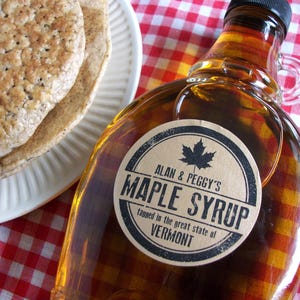 May include: A glass bottle of maple syrup with a brown paper label that reads "Alan & Peggy's Maple Syrup tapped in the great state of Vermont".