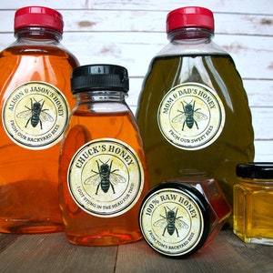 May include: Four glass jars of honey with labels featuring bee illustrations and text. The labels read "Alison & Jason's Honey", "Chuck's Honey", "Mom & Dad's Honey", and "100% Raw Honey".