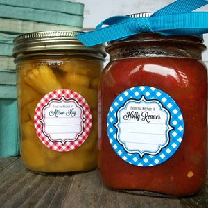 May include: Two glass jars with red and blue gingham patterned labels. The labels have a white background with black text that reads "From the Kitchen of Alison Kay" and "From the Kitchen of Holly Renner".