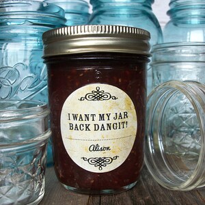 May include: A glass jar filled with a dark red substance, with a white label that reads "I WANT MY JAR BACK DANGIT!" and "Alison". The jar is surrounded by other glass jars.