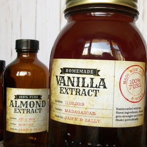 May include: Several amber glass bottles with black caps and labels. The labels read "Homemade Vanilla Extract" and "100% Pure Almond Extract." The vanilla extract is bottled on 11.05.2019 and made with Madagascar vanilla.