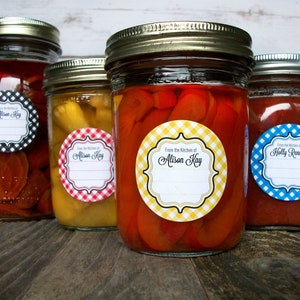 May include: Four glass jars with lids, each with a round label. The labels are white with black text and a gingham pattern in different colors. The text on the labels reads "From the Kitchen of Alison Kay" and "From the Kitchen of Holly Renner".
