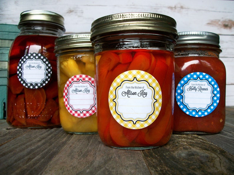 May include: Four glass jars with lids, each with a round label. The labels are white with black text and a gingham pattern in different colors. The text on the labels reads "From the Kitchen of Alison Kay" and "From the Kitchen of Holly Renner".