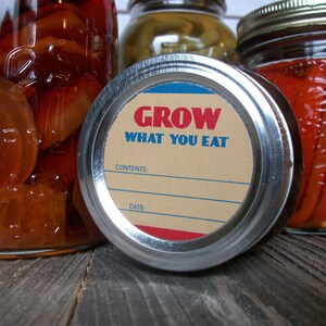 May include: A silver jar lid with a brown label that reads "GROW WHAT YOU EAT". The label has blue and red accents and blank lines for "CONTENTS" and "DATE".