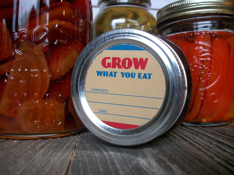 May include: A silver jar lid with a brown label that reads "GROW WHAT YOU EAT". The label has blue and red accents and blank lines for "CONTENTS" and "DATE".