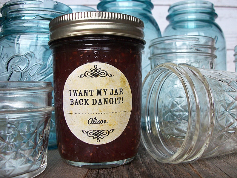 May include: A glass jar filled with a dark red jam with a round label that says "I WANT MY JAR BACK DANGIT!" with the name "Alison" below the text. The jar is surrounded by other glass jars.