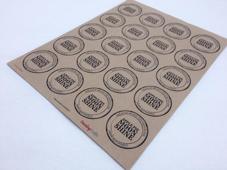 May include: A sheet of twenty circular brown kraft paper labels featuring black text that reads Apple Pie Moon Shine, XXX Home Brewed, Just For Your Kick, and Drink Responsibly. The CanningCrafts logo is printed in red at the bottom left.