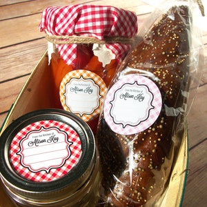May include: Three round labels with a gingham pattern in red and white, orange and white, and pink and white. The labels have a white border and the text "From the Kitchen of Alison Kay" in black script. The labels are on jars of preserves and a bag of bread.