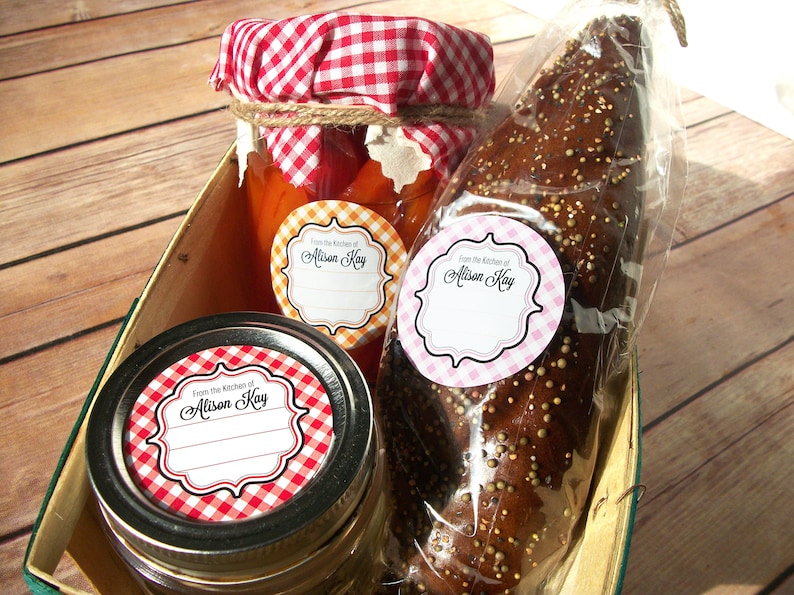 May include: Three round labels with a gingham pattern in red and white, orange and white, and pink and white. The labels have a white border and the text "From the Kitchen of Alison Kay" in black script. The labels are on jars of preserves and a bag of bread.