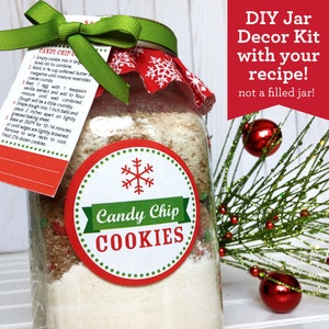 A DIY Candy Chip Cookies mason jar kit with a recipe tag and a green ribbon. The jar is decorated with a red and white snowflake fabric and a round label that says "Candy Chip COOKIES". The text "DIY Jar Decor Kit with your recipe!" is also visible.
