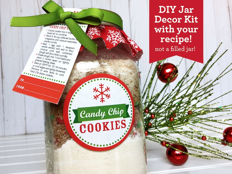 A DIY Candy Chip Cookies mason jar kit with a recipe tag and a green ribbon. The jar is decorated with a red and white snowflake fabric and a round label that says "Candy Chip COOKIES". The text "DIY Jar Decor Kit with your recipe!" is also visible.