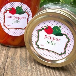 May include: Two glass jars with gold lids and red and white polka dot labels. The labels have green and red peppers on them and the text "hot pepper jelly" and "pepper jelly" with a space for a date.