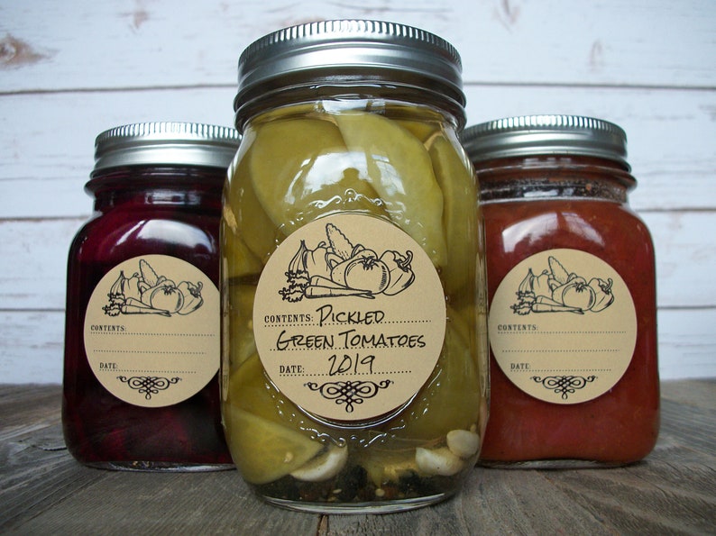 May include: Three glass jars with brown paper labels. The center jar contains pickled green tomatoes and has a label that reads "Contents: Pickled Green Tomatoes 2019".