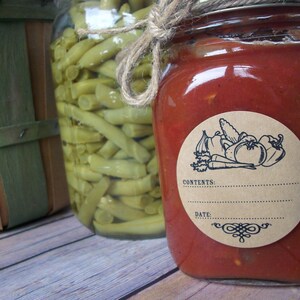May include: A glass jar filled with red tomato sauce with a brown paper label. The label has a black and white illustration of vegetables and the text "CONTENTS:" and "DATE:".