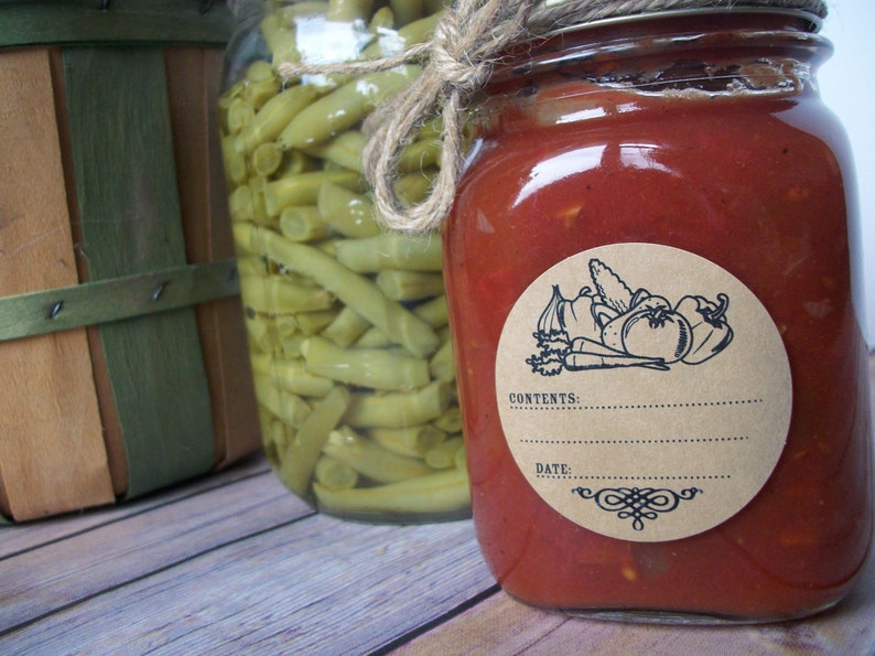 May include: A glass jar filled with red tomato sauce with a brown paper label. The label has a black and white illustration of vegetables and the text "CONTENTS:" and "DATE:".