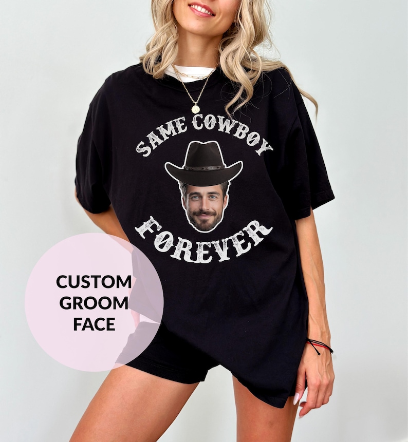 May include: Black t-shirt with the text "Same Cowboy Forever" in white lettering. A cowboy hat with a man's face is in the centre of the text. The text "Custom Groom Face" is in a pink circle in the bottom left corner of the image.