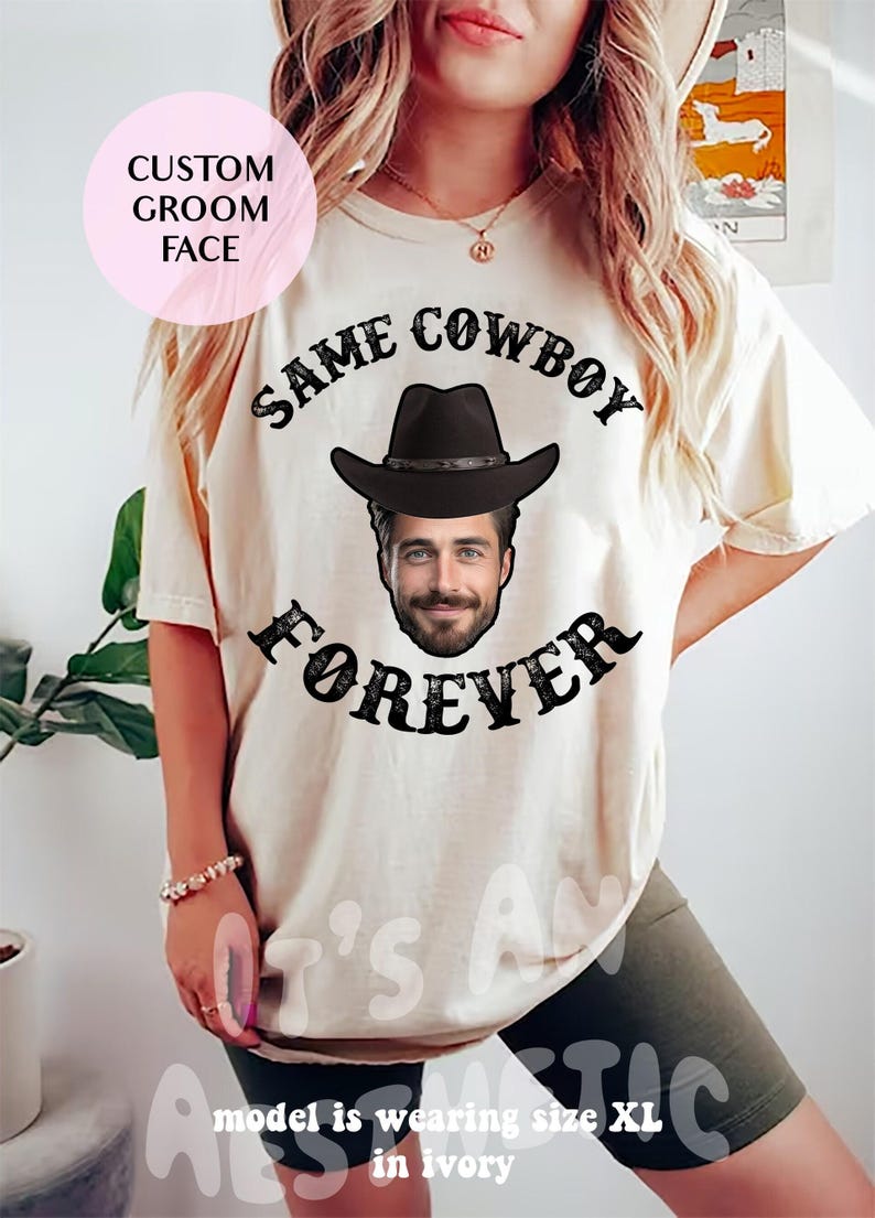 May include: A white t-shirt with the text "Same Cowboy Forever" in black. A cowboy hat with a face is in the centre of the text. The model is wearing size XL in ivory.