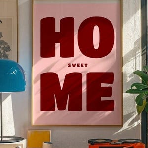 Peut inclure: Une affiche murale rectangulaire dans un cadre doré fin présentant un fond rose clair avec le texte en lettres capitales épaisses rouge foncé "HO" sur la ligne supérieure, "SWEET" en plus petit au milieu et "ME" sur la ligne inférieure.