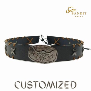 May include: Black leather choker with brown stitching and a silver-coloured metal buckle featuring a bull's head design. The choker has an adjustable closure and the word "CUSTOMIZED" is printed below.