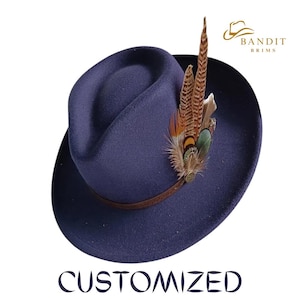 Op de afbeelding: Een marineblauwe fedora hoed met een bruine leren band. De hoed is versierd met een cluster van kleurrijke veren. Het woord "CUSTOMIZED" staat in een donkerblauwe lettertype onderaan de afbeelding. De hoed heeft het "Bandit Brims" logo.