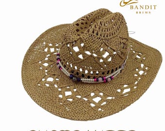 Puede incluir: Un sombrero de vaquero de paja tejida con una banda de cuentas decorativa. El sombrero presenta un ala ancha con un patrón recortado y el texto "CUSTOMIZED". El sombrero está marcado con el texto "BANDIT BRIMS".
