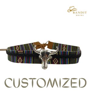 May include: A customized choker with a silver bull skull pendant. The choker features a patterned fabric band in shades of green, red, blue, and yellow. The text "CUSTOMIZED" is at the bottom, and the "BANDIT BRIMS" logo is at the top.