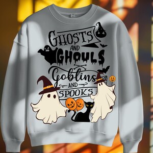 May include: A light gray sweatshirt with a Halloween-themed graphic. The design features the words "Ghosts and Ghouls, Goblins and Spooks" with illustrations of ghosts, bats, a black cat, and jack-o'-lanterns. The sweatshirt has a crew neck and long sleeves.