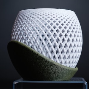 Peut inclure: Un pot en céramique blanche avec un motif de treillis géométrique. Le pot a une base verte et est posé sur une surface en verre transparent.