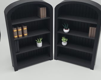 Pode incluir: Duas estantes pretas com tampo arqueado e várias prateleiras. Cada prateleira contém livros em miniatura e pequenas plantas em vasos. As prateleiras estão dispostas sobre um fundo branco.