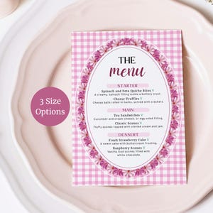 May include: A rectangular menu card with a pink and white gingham background, featuring an oval frame of pink flowers. The text reads THE menu, STARTER, Spinach and Feta Quiche Bites, Cheese Truffles, MAIN, Tea Sandwiches, Classic Scones, DESSERT, Fresh Strawberry Cake, Raspberry Scones. A pink circle states 3 Size Options.