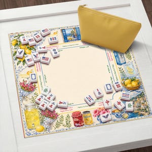 May include: A mahjong set with tiles, a decorative mat, and a yellow zippered pouch. The mat features a floral and lemon design with text. The tiles have various symbols and markings. The set is on a white surface.