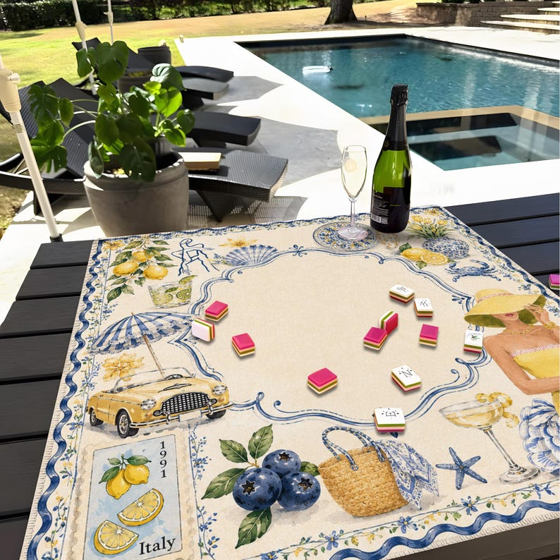 May include: A decorative table mat with a vintage Italian theme. The mat features illustrations of lemons, a yellow convertible, blueberries, and a woman in a yellow dress. A bottle of champagne and a glass are on the table, along with game pieces.