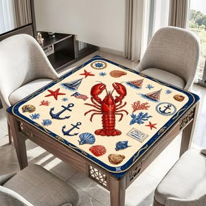 May include: Square table cover with a nautical theme. The cream-colored cover features a large red lobster, anchors, sailboats, seashells, and starfish. A navy blue rope border frames the design.