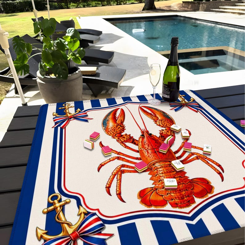 May include: A decorative lobster-themed game board with a red, white, and blue nautical design. The board features a large illustration of a lobster, surrounded by game pieces and anchor motifs. A bottle of champagne and a glass are on the table.