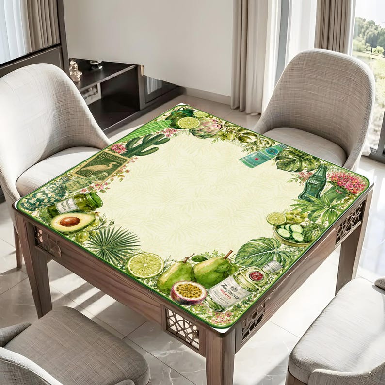 Puede incluir: Una mesa cuadrada de madera con una encimera decorativa con borde verde que presenta un dise&ntilde;o de acuarela de frutas, verduras y botellas. La mesa est&aacute; rodeada de sillas, creando un ambiente de comedor o sala de estar.