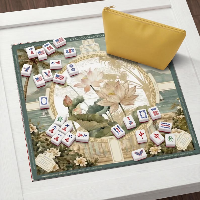 May include: A Mahjong game set featuring a rectangular play mat with a lotus flower illustration and the text "DRACO'S COLLECTION" and "CHARLESTON". The set includes white tiles with various symbols and American flag designs, plus a yellow pouch.