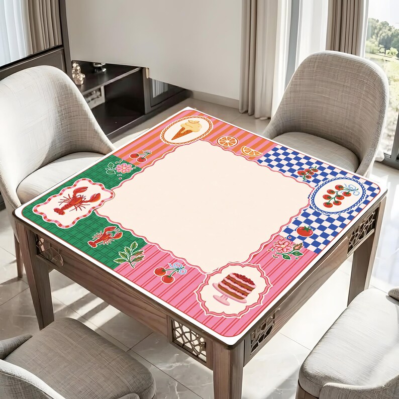 May include: A square table with a decorative mat featuring a central cream-colored area surrounded by colorful borders. The borders include illustrations of food items like lobster, cherries, and cake. The table is made of wood.