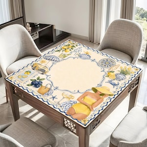 May include: A square table with a decorative beach-themed tablecloth. The tablecloth features illustrations of lemons, blueberries, seashells, and a woman in a yellow swimsuit. The table is made of wood and has a decorative lattice design on the sides.