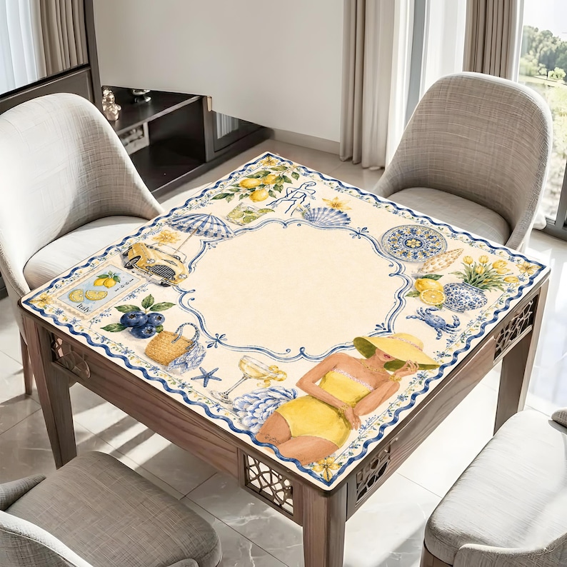 May include: A square table with a decorative beach-themed tablecloth. The tablecloth features illustrations of lemons, blueberries, seashells, and a woman in a yellow swimsuit. The table is made of wood and has a decorative lattice design on the sides.