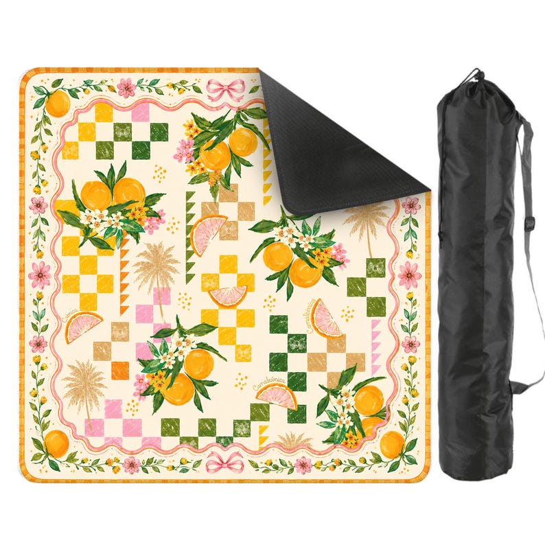 May include: A picnic blanket with a cream background featuring a pattern of oranges, flowers, and checkered squares. The blanket has a black underside and comes with a black carrying bag. The design includes pink, yellow, and green accents.