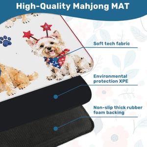 May include: A rectangular mahjong mat featuring a white surface with illustrations of dogs wearing star headbands and patriotic bandanas. The mat is composed of a soft tech fabric top layer, an environmental protection XPE middle layer, and a non-slip thick rubber foam backing.