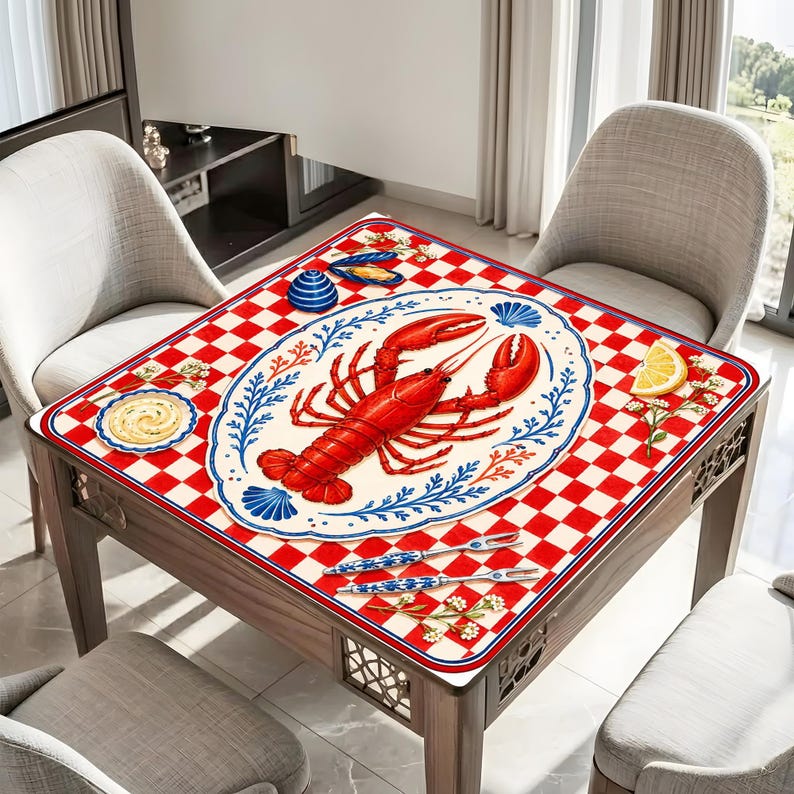 Op de afbeelding: Een vierkante houten tafel met een rood-wit geblokt patroon. De tafel is versierd met een kreeften- en zeevruchtenontwerp. De kreeft is rood en het ontwerp bevat een bord, een citroenpartje en bestek.
