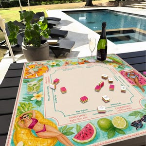 Op de afbeelding: Een kleurrijk bordspel met een tropisch thema, met illustraties van een vrouw op een ananasvlot, watermeloen en cocktails. Het spel bevat roze en witte tegels, een fles champagne en een glas.