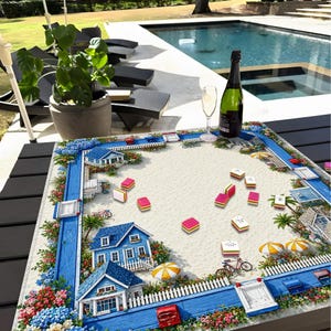 May include: A decorative game board with a beach scene, featuring miniature blue houses, white picket fences, and colorful flowers. Pink and yellow game pieces are scattered across the sandy surface. A bottle of champagne and a glass are on the table.