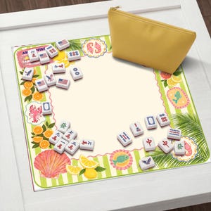 May include: A yellow zippered pouch rests on a decorative mat with a tropical theme. The mat features illustrations of oranges, lemons, and seafood, along with Mahjong tiles. The tiles display various symbols and numbers.